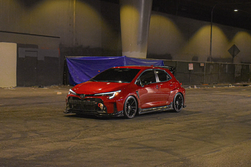 Load image into Gallery viewer, Gloss black V2 front lip installed on a red Toyota GR Corolla (E210, 2023-2024) parked at night.