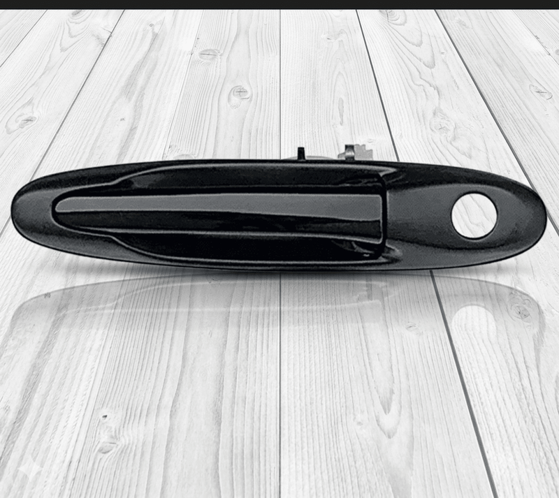 Load image into Gallery viewer, Genuine black Toyota Supra MK4 exterior door handle assembly on a wooden background.