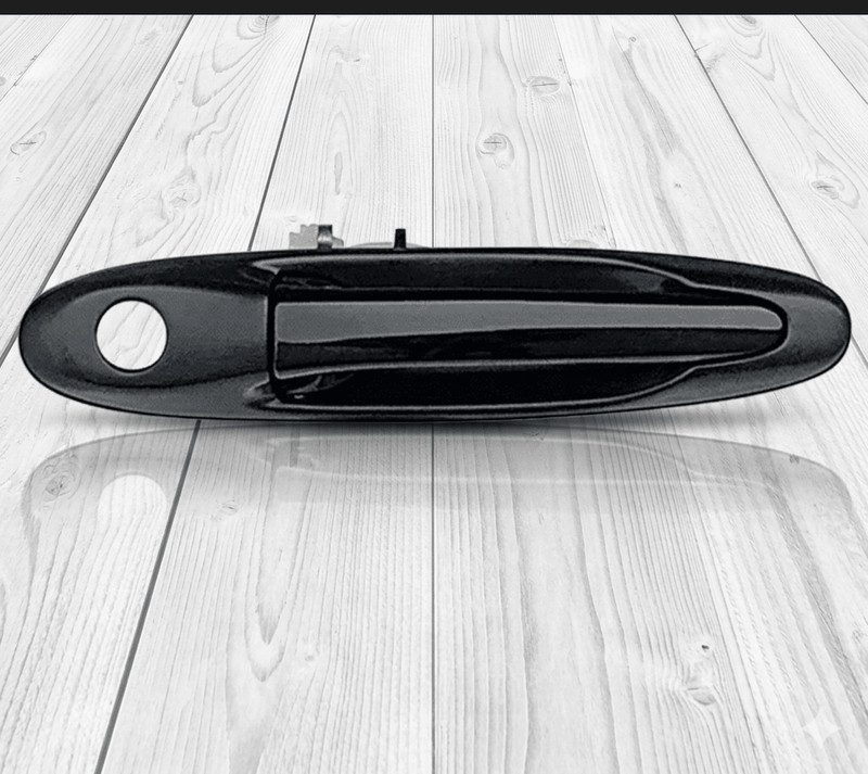 Load image into Gallery viewer, Genuine unpainted black exterior door handle assembly for Toyota Supra MK4 on a wooden background.