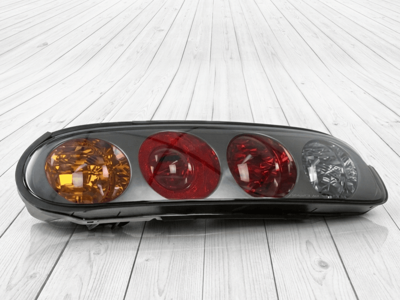 ギャラリービューアに画像をロードする, Genuine Toyota MK4 Supra taillight assembly with amber, red, and clear lenses on a wood background.