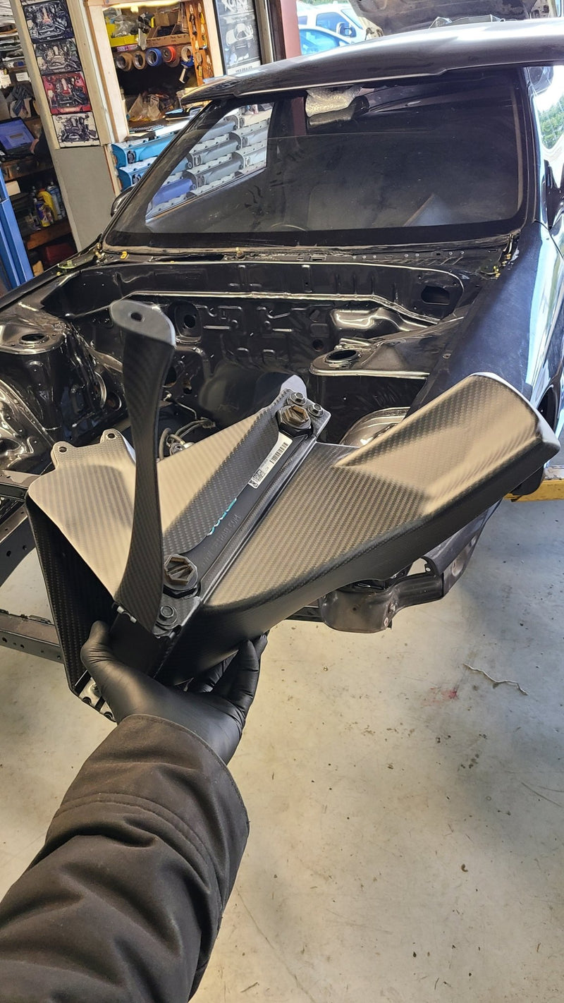 Load image into Gallery viewer, Gloved hand holding a carbon fiber-ducted oil cooler for an R32 GTR.