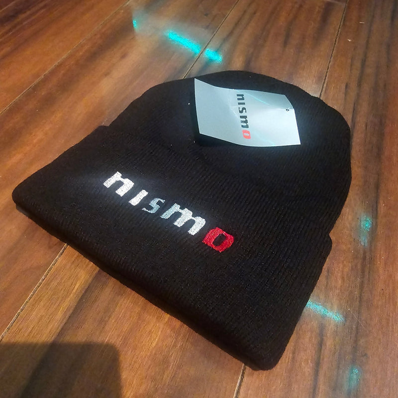 Load image into Gallery viewer, Black beanie with 'nismo' logo on a wooden surface