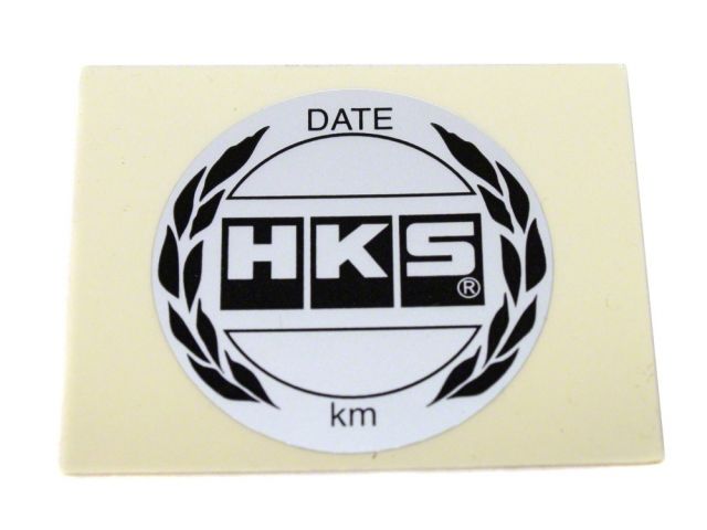 Load image into Gallery viewer, White HKS oil filter service reminder sticker for Nissan and Toyota models, featuring black logo and text.
