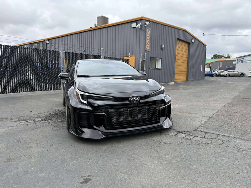 Load image into Gallery viewer, Gloss black front lip installed on a 2025+ Toyota GR Corolla (E210, Kouki) parked in a lot.
