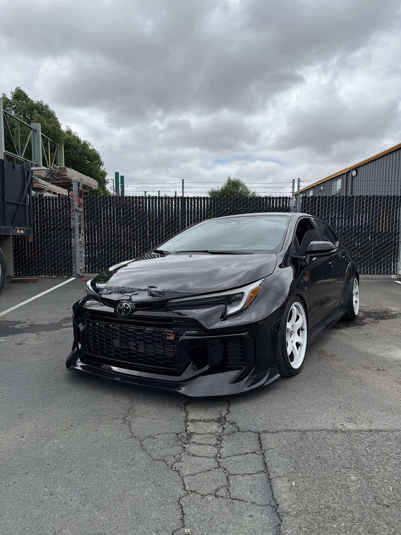 Load image into Gallery viewer, Gloss black front lip installed on a 2025+ Toyota GR Corolla (E210/Kouki) with white wheels.