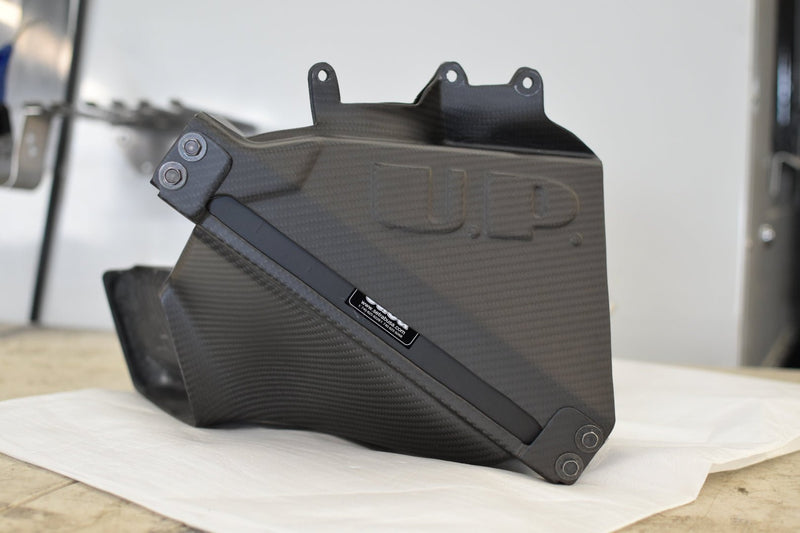 Load image into Gallery viewer, U.P.G. black carbon fiber oil cooler duct for Nissan R32 GTR. Features molded U.P. logo and Setrab branding.