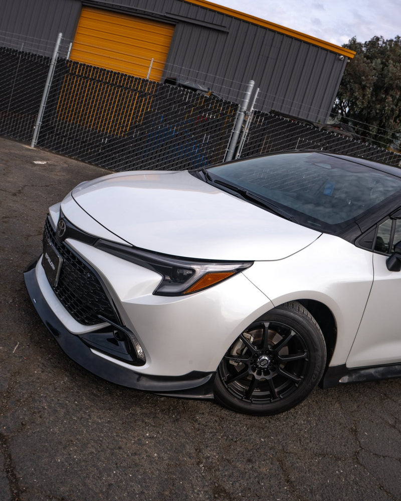 Load image into Gallery viewer, Gloss black front lip installed on a white 2023+ Toyota Corolla Hatchback (E210 Kouki).