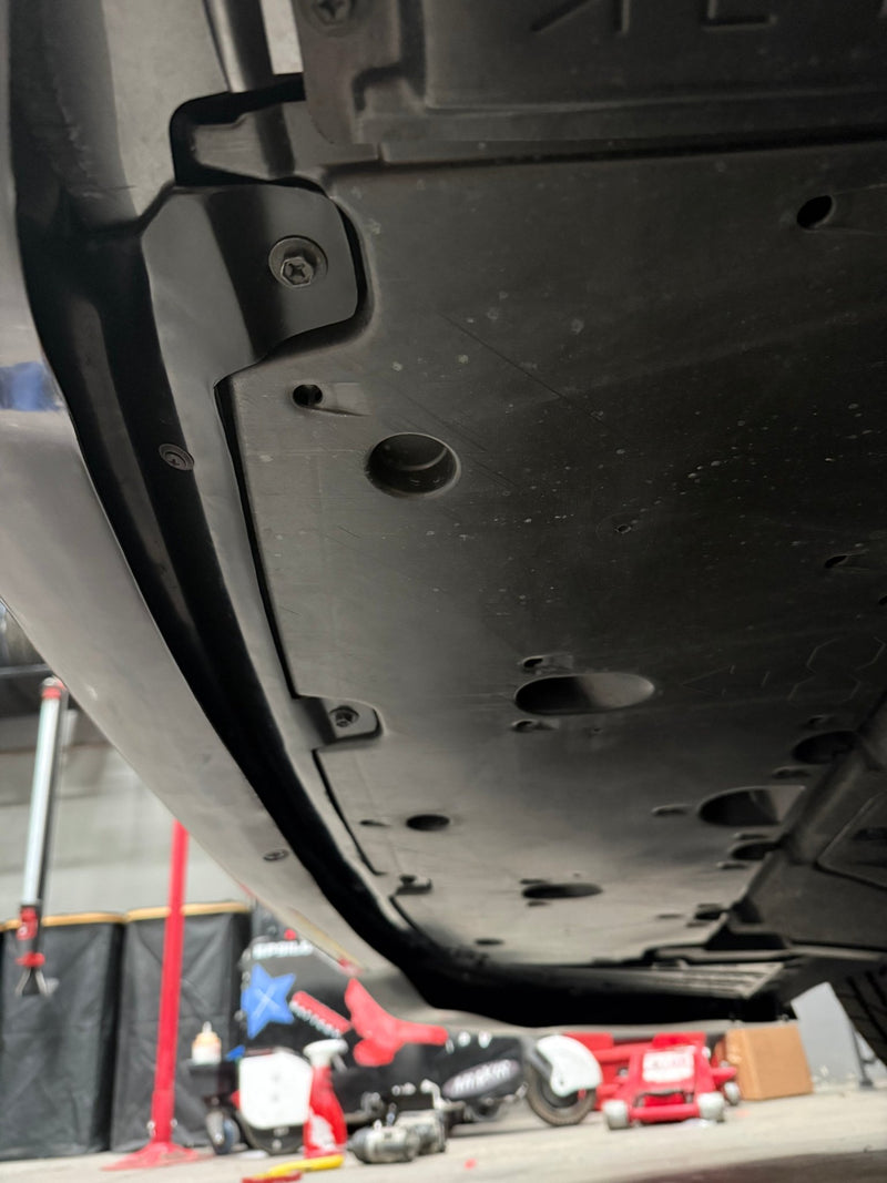 Load image into Gallery viewer, Underside view of a black front lip installed on a 2025+ Toyota GR Corolla (E210 Kouki) with mounting hardware.