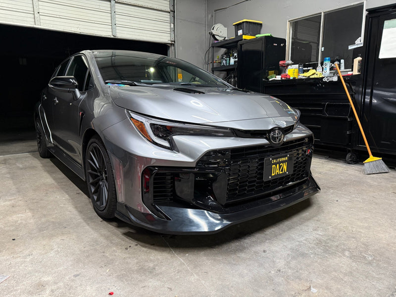 Load image into Gallery viewer, Gloss black front lip installed on a silver 2025 Toyota GR Corolla (E210 Kouki) in a garage.