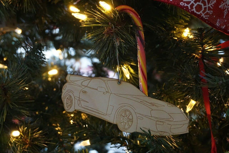 Load image into Gallery viewer, Laser-engraved light-colored birch wood ornament shaped like a Toyota Supra MKIV hanging on a Christmas tree.