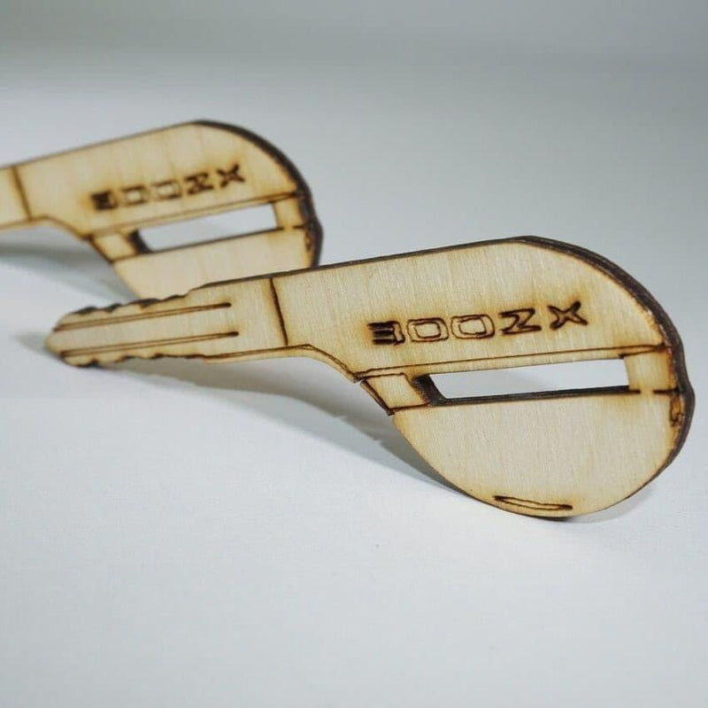 Load image into Gallery viewer, Two ZSPEC laser-engraved birch wood ornaments shaped like Nissan 300ZX Z32 keys.