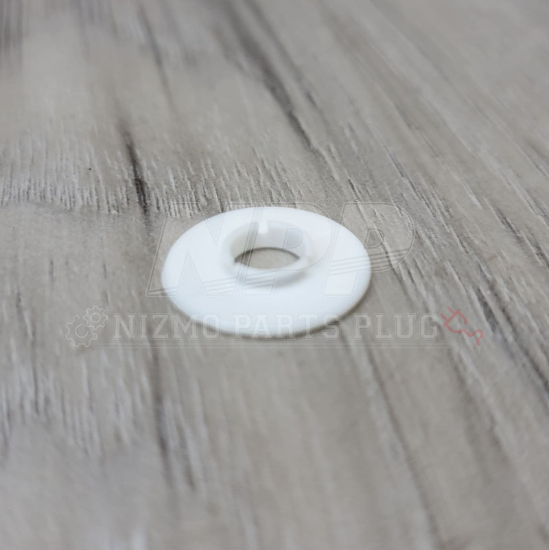 Load image into Gallery viewer, White plastic fender washer for Nissan R34 Skyline GTR on a wood grain background.