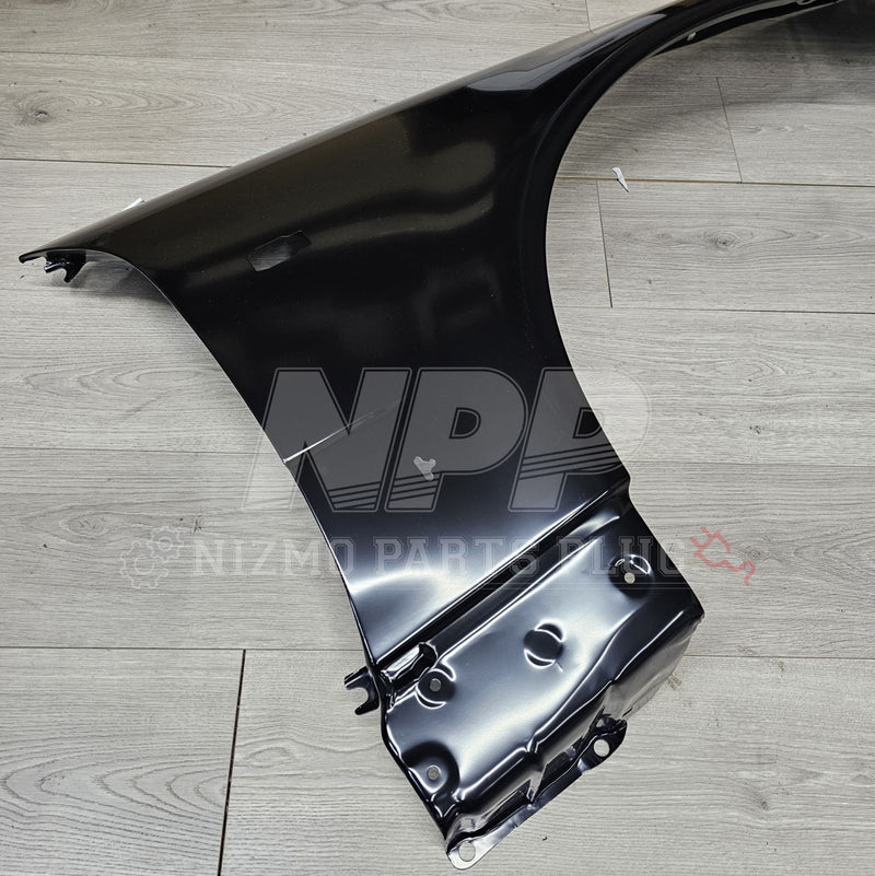 ギャラリービューアに画像をロードする, Black RH front fender assembly for Nissan R34 Skyline GTR, shown from above on a wood-grain surface.