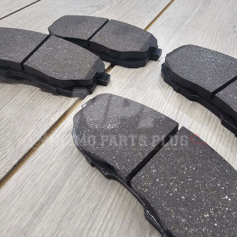 Load image into Gallery viewer, New black front brake pads for Nissan Stagea RS4-V on wooden surface.
