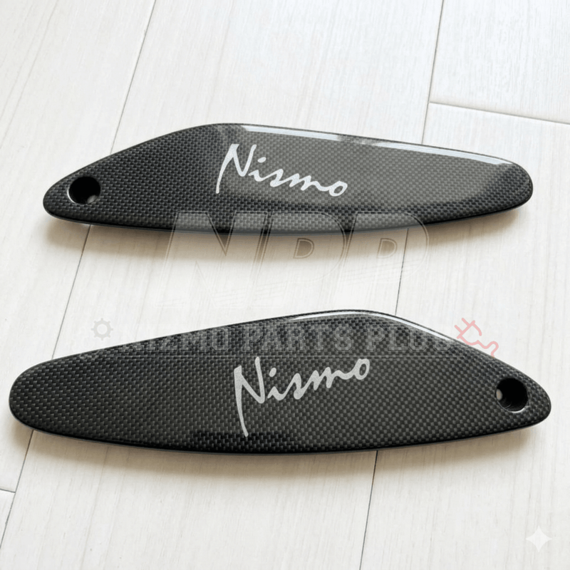Load image into Gallery viewer, Pair of glossy carbon fiber R33 GTR rear spoiler mid covers with white Nismo logos.