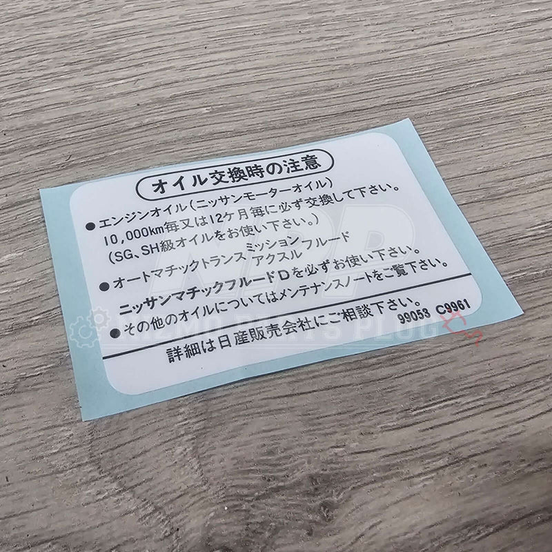 Load image into Gallery viewer, Nissan Skyline R33 R34 Oil Label Caution Decal on a wooden surface, showcasing oil change instructions and warnings.