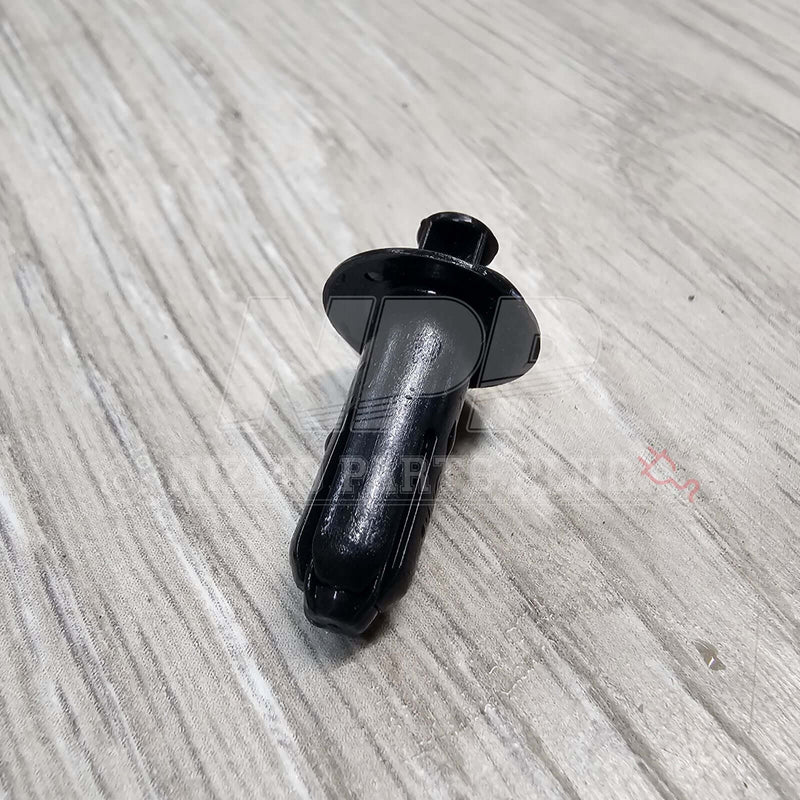 Load image into Gallery viewer, Black Nissan R34 Skyline interior door panel push mounting clip on a wood-grain surface.
