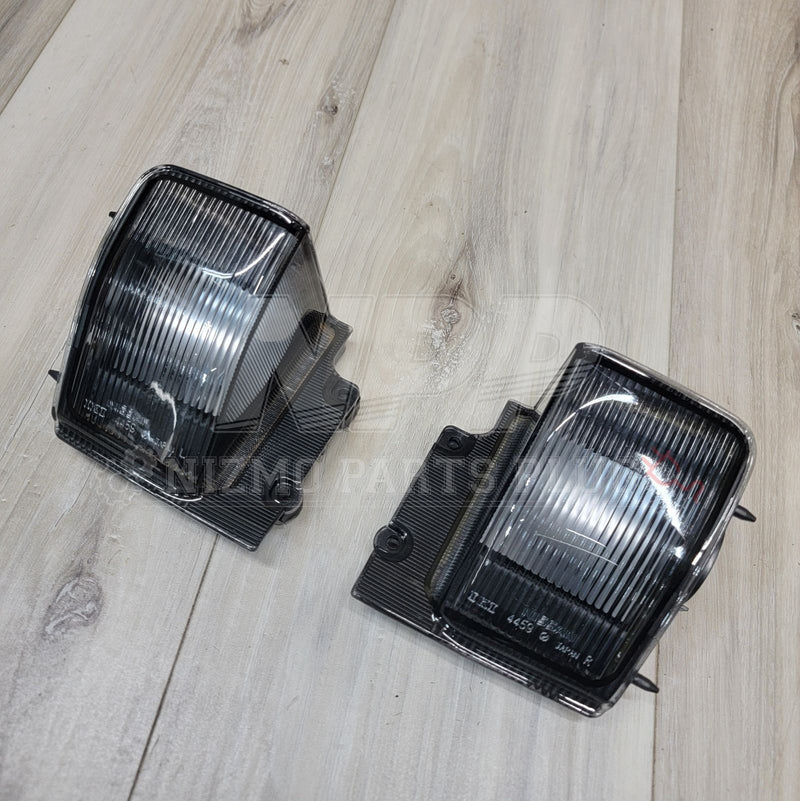 Load image into Gallery viewer, Pair of clear reverse light assemblies for Nissan R32 Skyline, featuring ribbed lenses and black plastic housings.