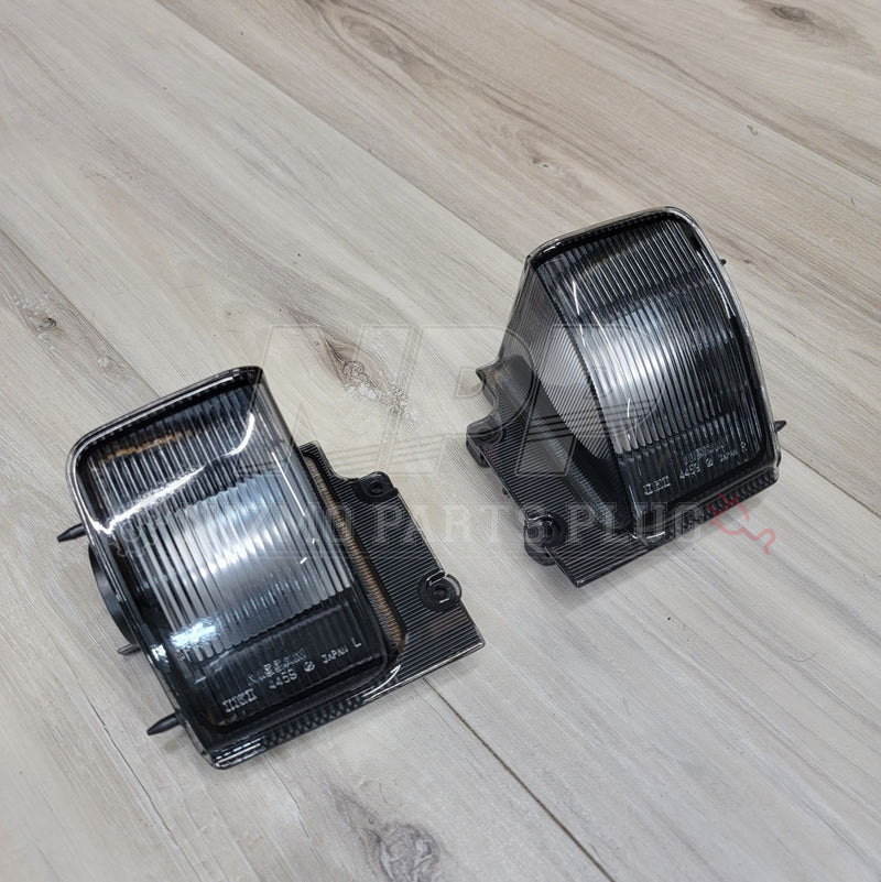 Load image into Gallery viewer, Nissan R32 Skyline Coupe clear reverse light assembly set in excellent condition on a wood floor.