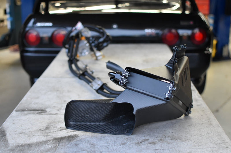 Load image into Gallery viewer, Complete black carbon fiber oil cooler kit for R32 GTR with hoses, sitting on a table in front of an R32 GTR.