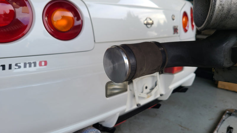 Load image into Gallery viewer, Silver 50mm BOV plug installed on a black intake hose in front of a white Nissan Skyline R34 GT-R.