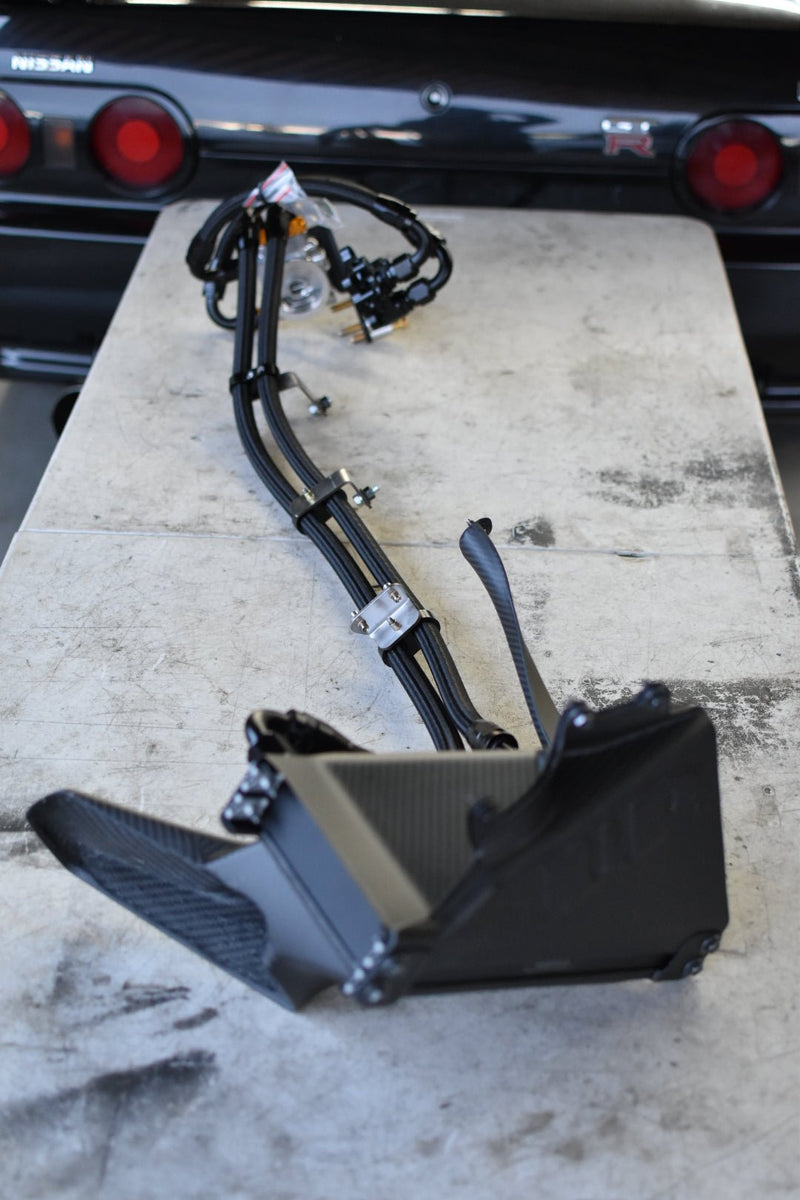 Load image into Gallery viewer, Complete UPG oil cooler kit with carbon fiber ducting for R32 GTR on a workbench in front of a Nissan Skyline.