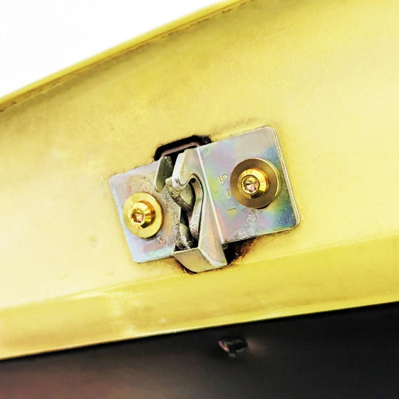 Load image into Gallery viewer, ZSPEC titanium gold trunk bolts installed on a Datsun S30 hatch latch mechanism against a yellow painted surface.