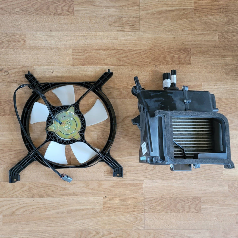 Load image into Gallery viewer, N.O.S. S13 240SX R134A A/C kit with black cooling fan and heater core assembly on wood floor.