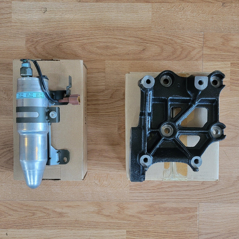 Load image into Gallery viewer, N.O.S. S13 240SX R134A A/C kit, including a silver receiver dryer and black compressor mounting bracket.