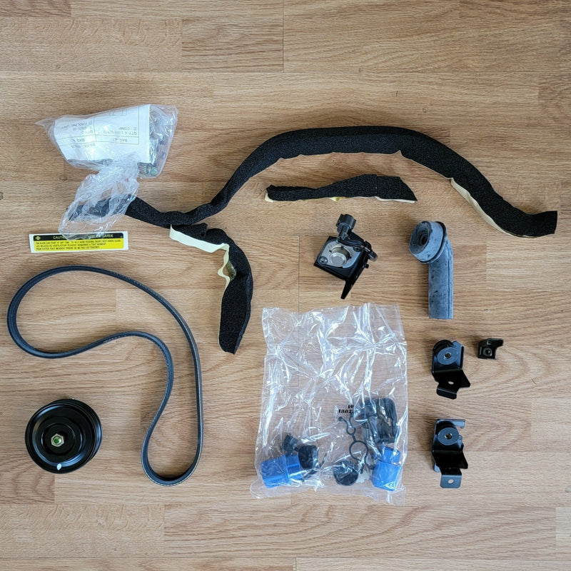 Load image into Gallery viewer, New old stock S13 240SX A/C installation kit including belt, pulley, hardware, and foam insulation on wood background.