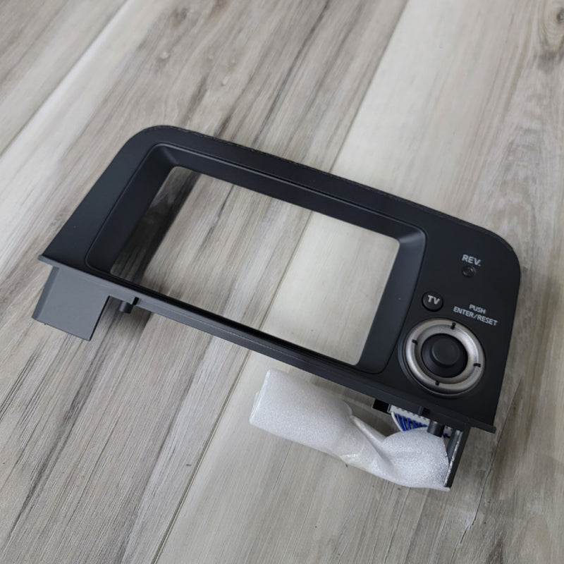 Load image into Gallery viewer, Black R34 Skyline GTR Multi Function Display controller bezel with adjustment dial on a wood floor.