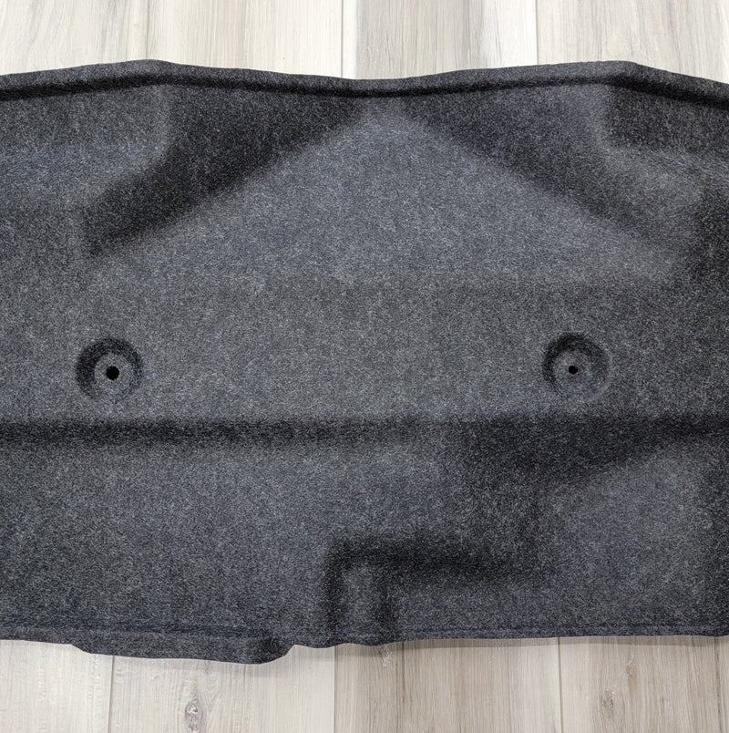 Load image into Gallery viewer, Dark gray carpeted R34 Skyline GT-R trunk battery finisher panel in clean, pre-owned condition.