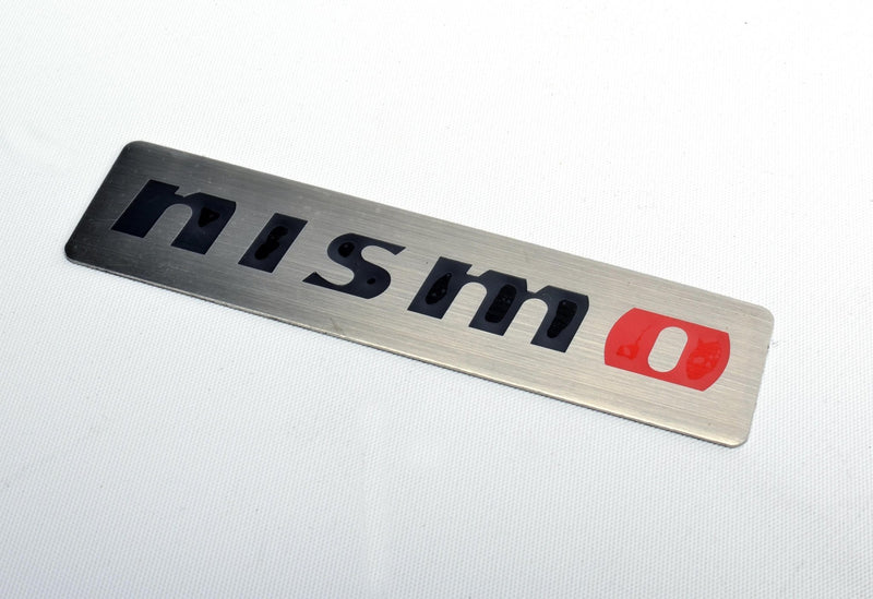 Load image into Gallery viewer, Brushed aluminum Nismo emblem badge for Nissan models, featuring black lettering and a red "o" on a rectangular plate.