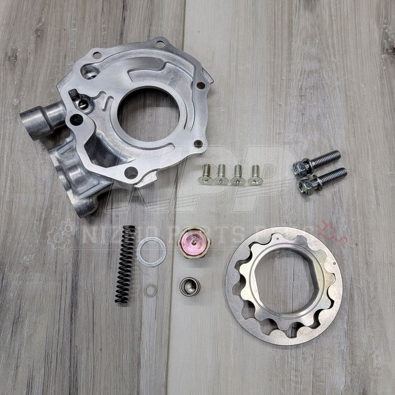 Load image into Gallery viewer, New silver Nissan S13 240SX KA24DE engine oil pump kit with housing, rotor, spring, and hardware on a wood surface.
