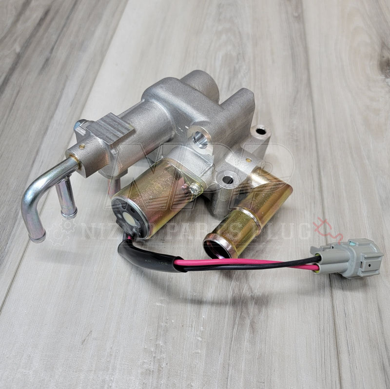 Load image into Gallery viewer, Nissan R34 Skyline GTT idle air control valve with silver metallic housing and gold-tone ports on wood surface.