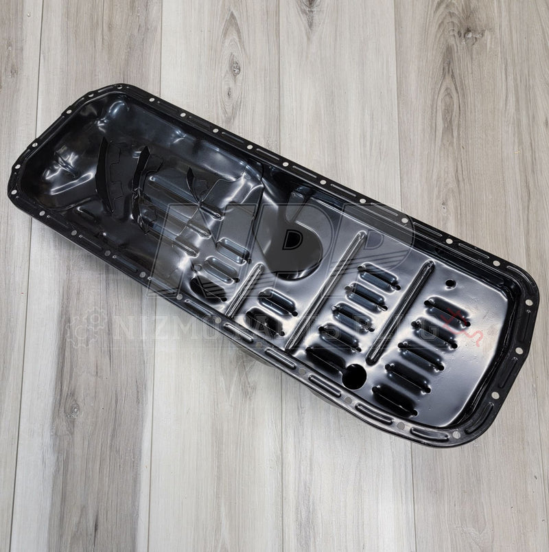 Load image into Gallery viewer, Black Nissan Skyline RB20/RB25 RWD oil pan assembly on wood background. Excellent, clean condition.