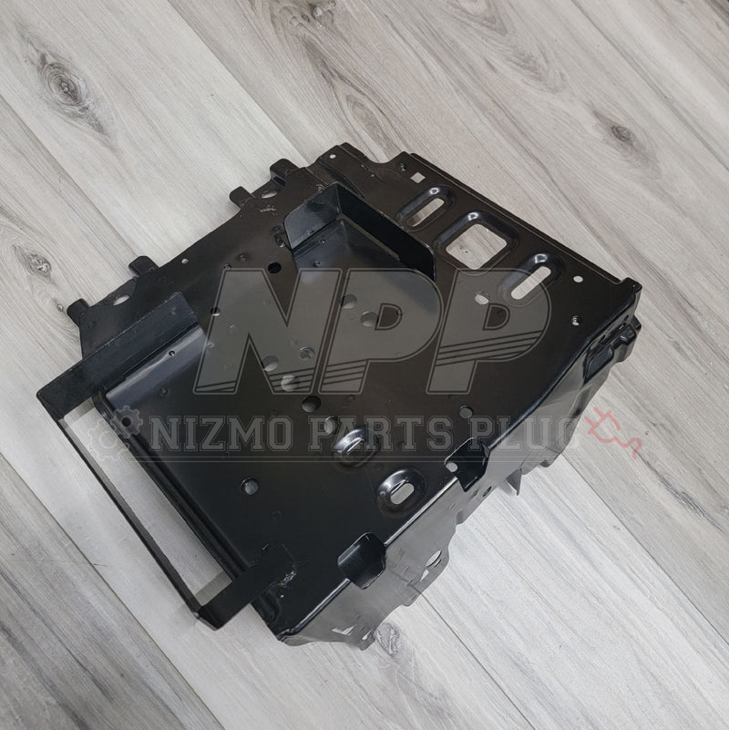 Load image into Gallery viewer, Black Nissan R34 Skyline GTR cold weather battery bracket assembly on a wood grain background.