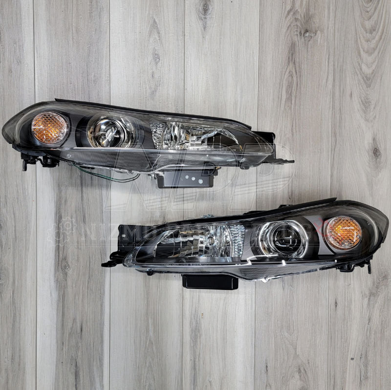 Load image into Gallery viewer, OEM Nissan S15 Silvia HID headlight assembly set with black housings and clear lenses on a wood background.