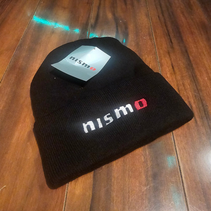 Load image into Gallery viewer, Black knit beanie with 'nismo' logo on a wooden surface
