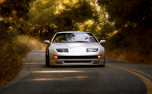 Silver sports car on a winding road surrounded by trees