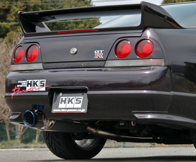 Load image into Gallery viewer, HKS Super Turbo Muffler installed on a dark purple Nissan Skyline GT-R BCNR33, featuring a blue-burnt titanium tip.
