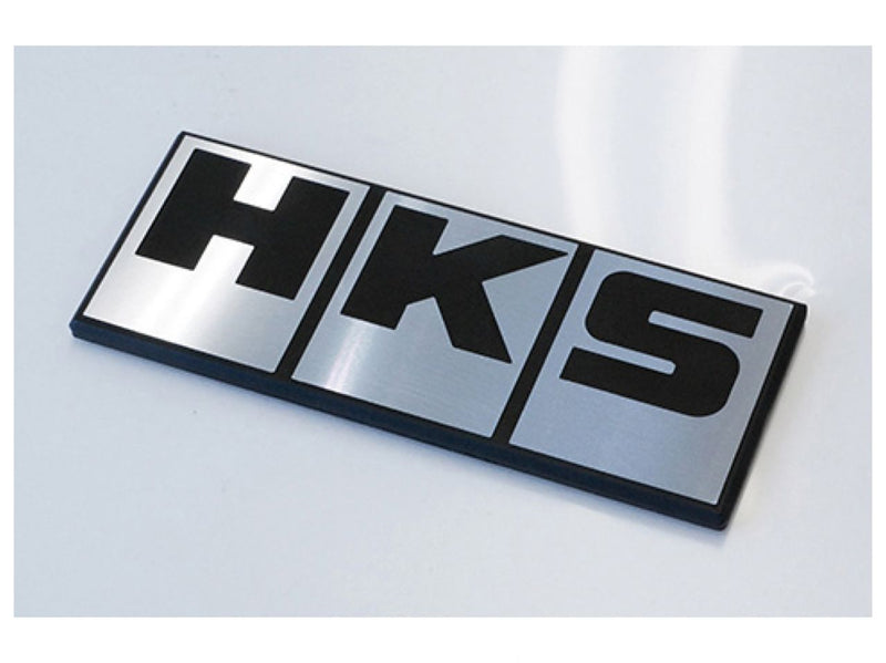 Load image into Gallery viewer, Silver and black HKS emblem for JDM vehicles, featuring clean, metallic finish on a white background.
