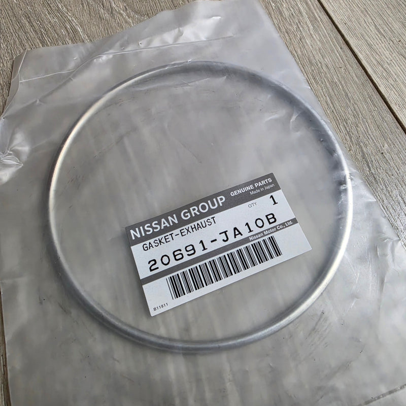 Load image into Gallery viewer, New genuine Nissan silver exhaust crush gasket, OEM part 20691-JA10B, in original sealed plastic packaging.
