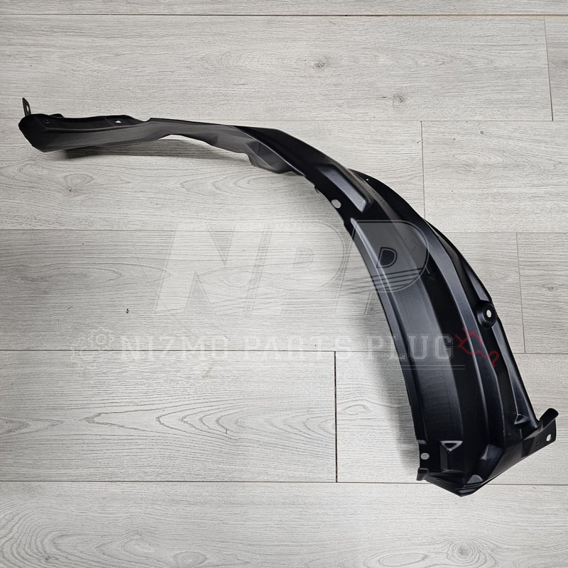 Load image into Gallery viewer, Black Nissan R34 Skyline GTR front fender wheel liner protector on a wood grain background.
