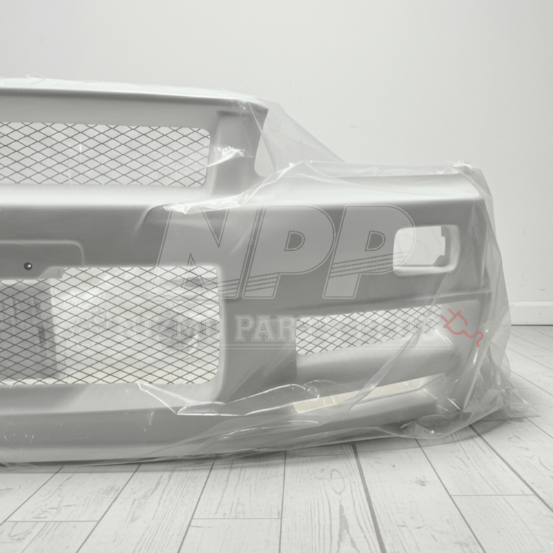 Load image into Gallery viewer, New white Nissan R34 Skyline GTR Nismo Z-Tune front bumper in protective plastic packaging.

