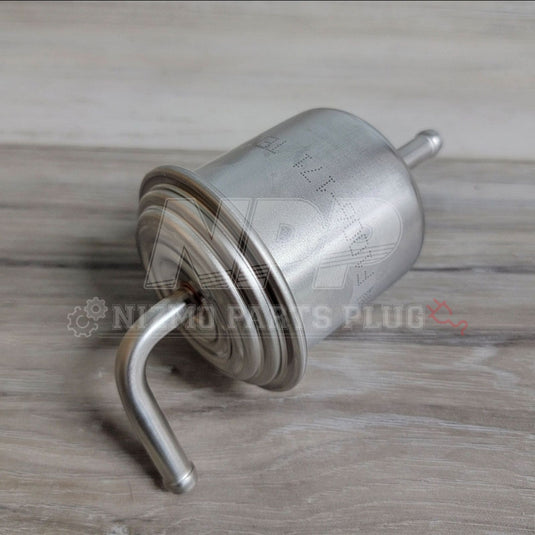 Metallic fuel filter on a wooden surface with 'Nismo Parts Plug' branding.