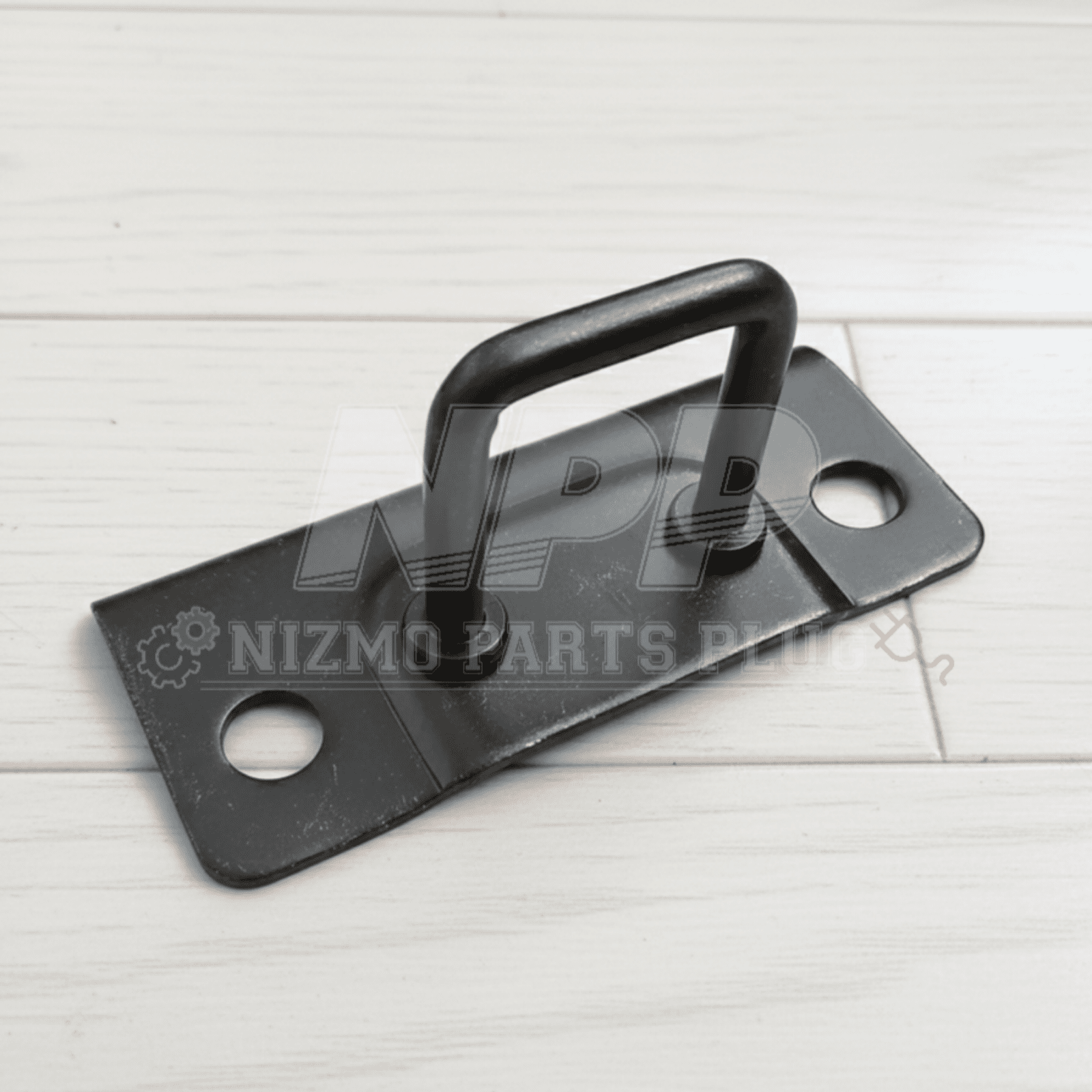 Black metal plate with handle on a white wooden surface, branded 'Nizmo Parts'.