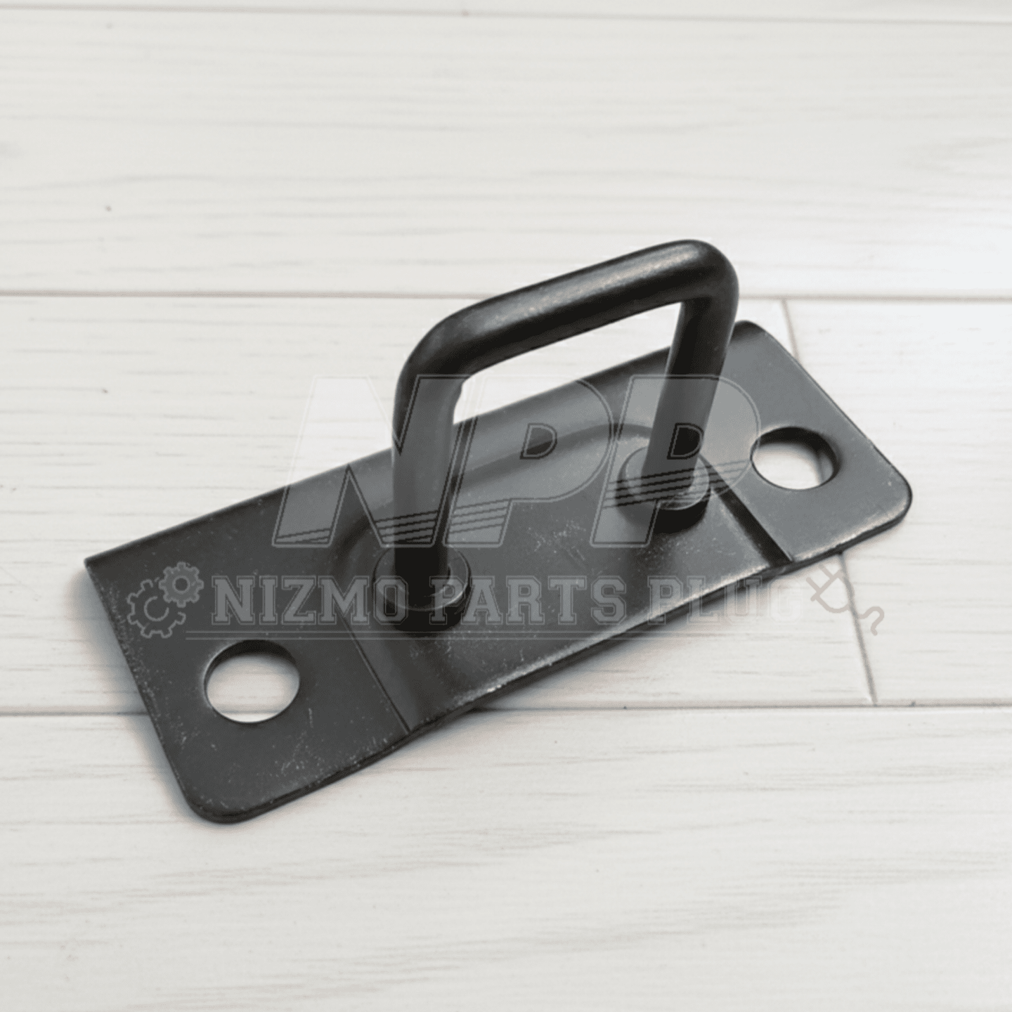 Black metal plate with handle on a white wooden surface, branded 'Nizmo Parts'.