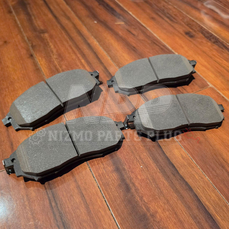 Load image into Gallery viewer, Set of four new grey front brake pads for Nissan Stagea RS4-V (11/1998 build) arranged on a wooden floor.
