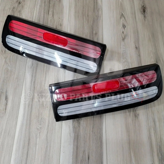 Pair of rectangular red and clear car tail lights on wooden floor